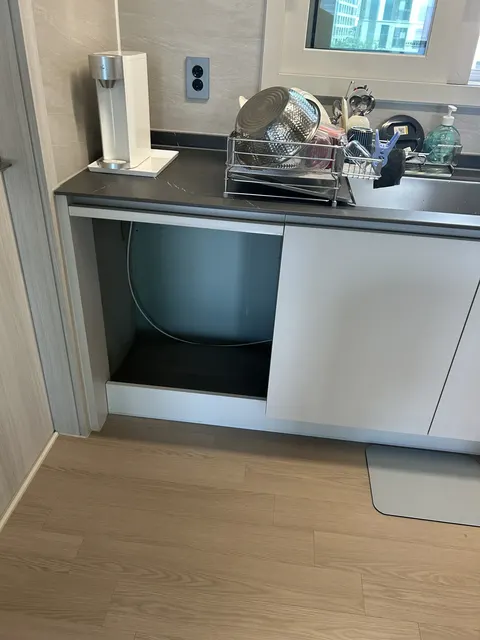 싱크대 하부장 교체 전 현장 현장 사진, 상판 아래 한쪽이 비어 있고 흰색 도어가 한 짝 달린 싱크대 하부