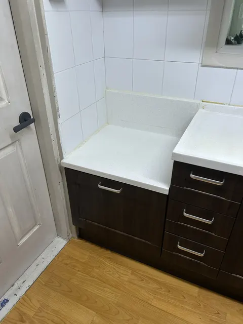 싱크대 하부장 교체 전 현장 현장 사진, 짙은 갈색 하부장 도어와 3단 서랍이 있는 좁은 주방 코너